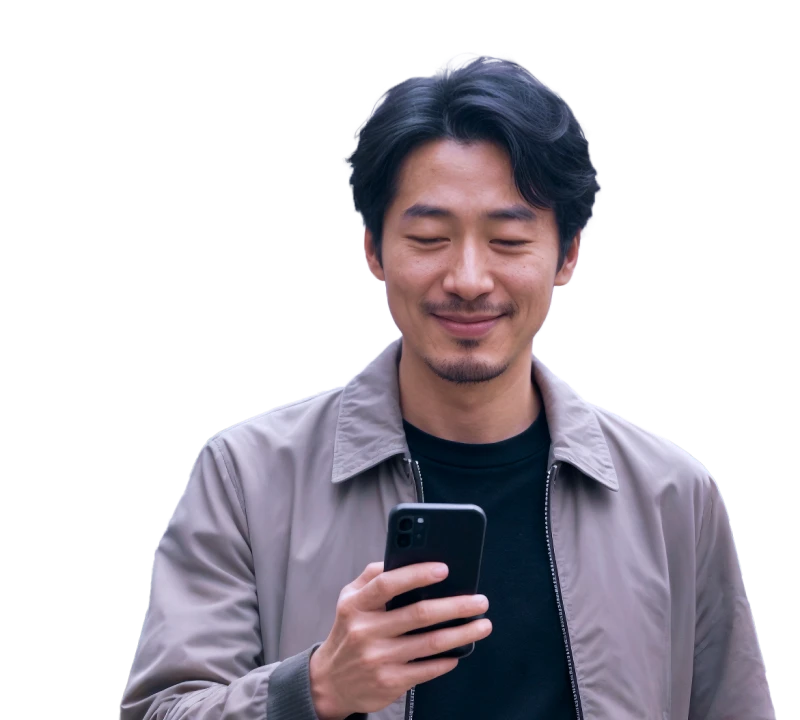 Smiling man looking at his smartphone outdoors, standing on a city street with a blurred urban background