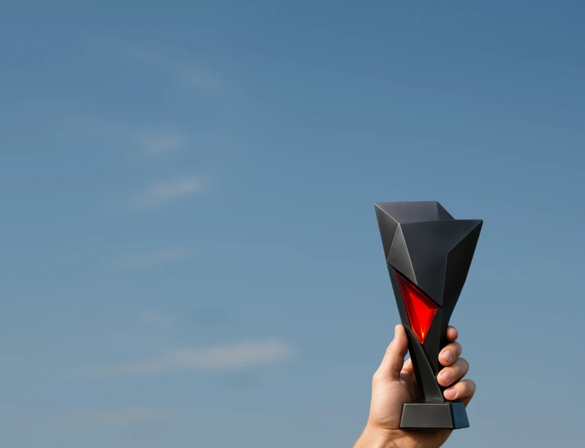 XMTrading affiliates league promotion illustrated with a hand holding a trophy against a clear sky