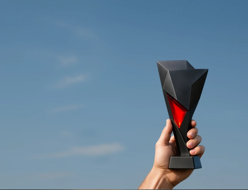 XMTrading affiliates league promotion illustrated with a hand holding a trophy against a clear sky