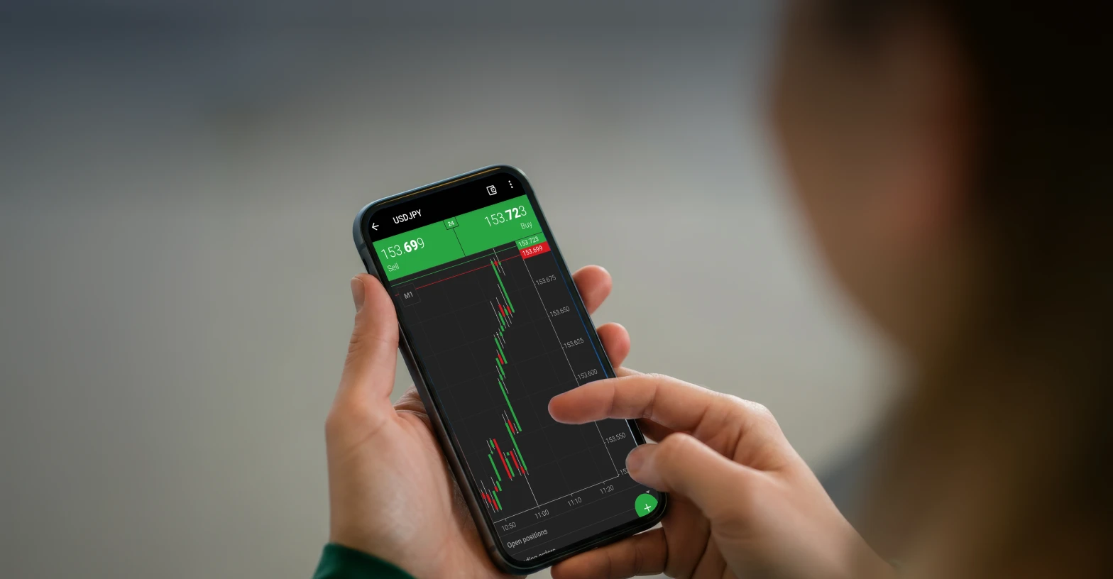 A person using a XMTrading app displaying forex trading charts, symbolising growth and rewards through active trading.