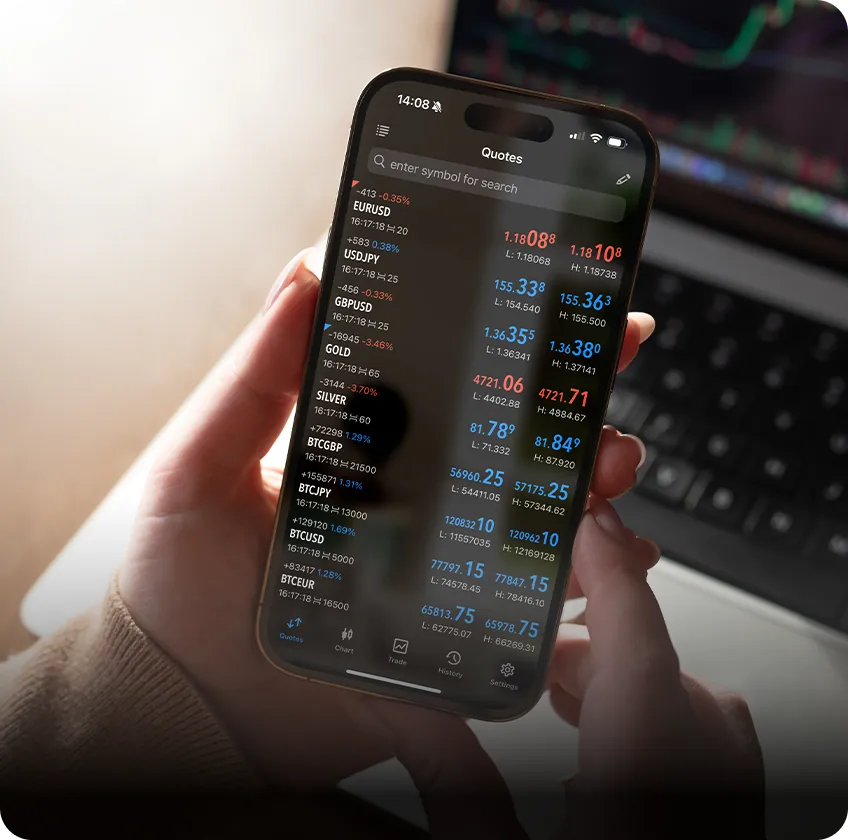 Hand holding smartphone with XMTrading live market quotes.