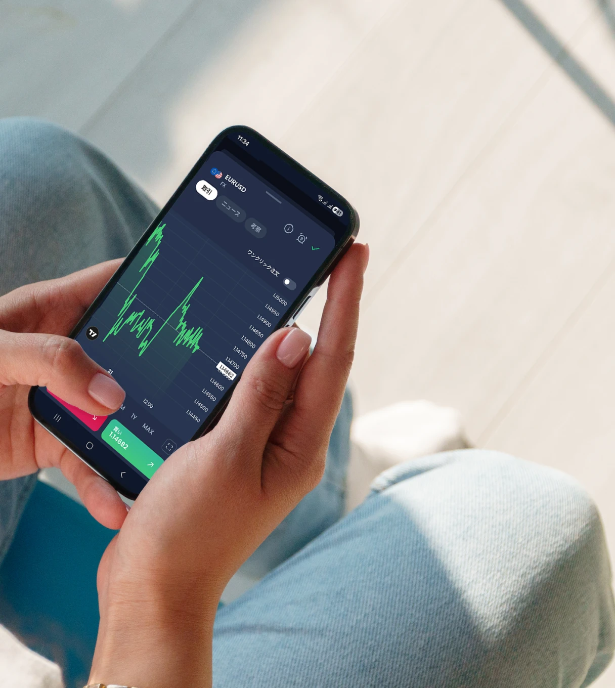 A person holding a smartphone showing a live EUR/USD trading chart with red and green candlesticks and buy/sell indicators.
