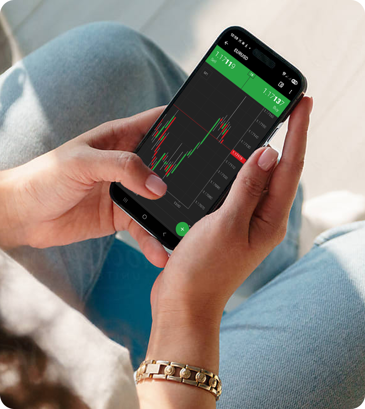 A person holding a smartphone showing a live EUR/USD trading chart with red and green candlesticks and buy/sell indicators.