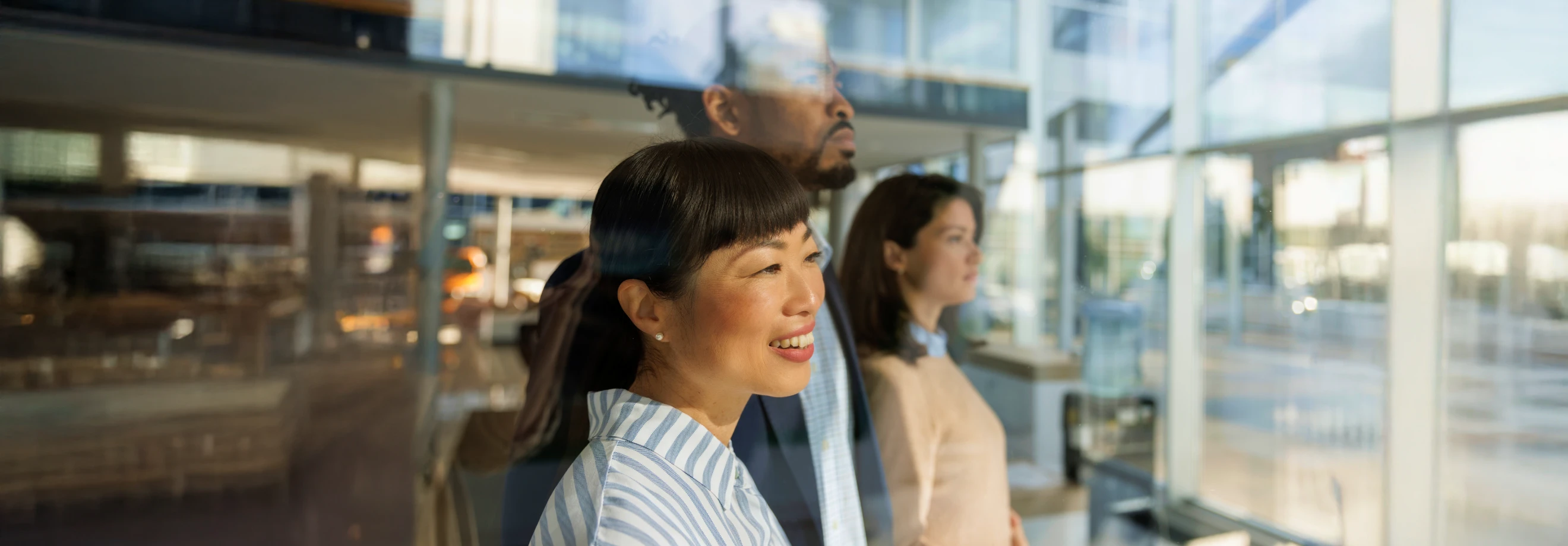 People looking ahead through bright office windows, symbolizing XMTrading’s vision, innovation, and commitment to traders.
