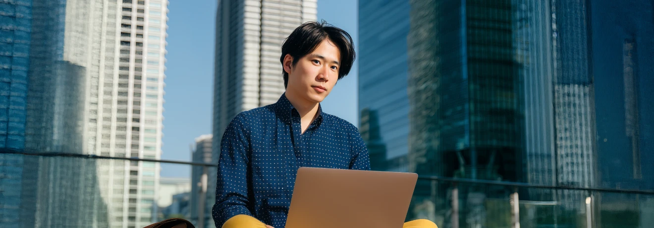 Man sitting with a laptop on a terrace, engaged in trading.