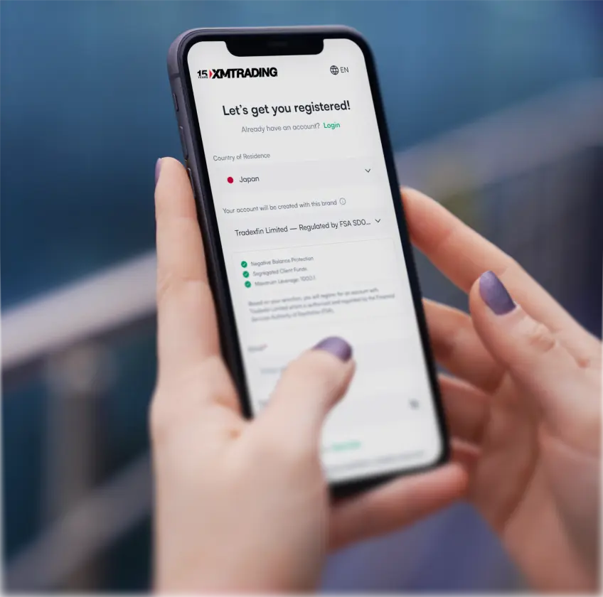 User completing the account registration process on a smartphone with the XMTrading sign-up form displayed.
